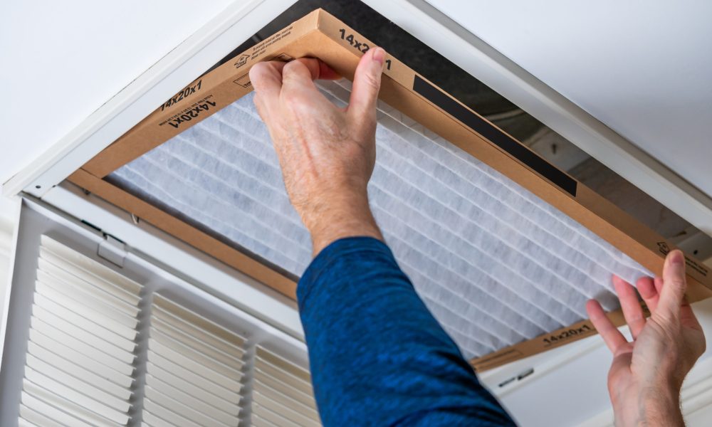 Man replacing dirty HVAC air filter in ceiling vent. Home air du